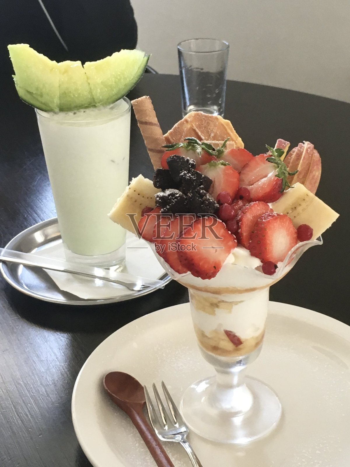 健康的早餐：草莓优格杯，搭配新鲜水果，摆放在乡村风格的白色桌子上。选择性对焦，背景和前景模糊。照片摄影图片