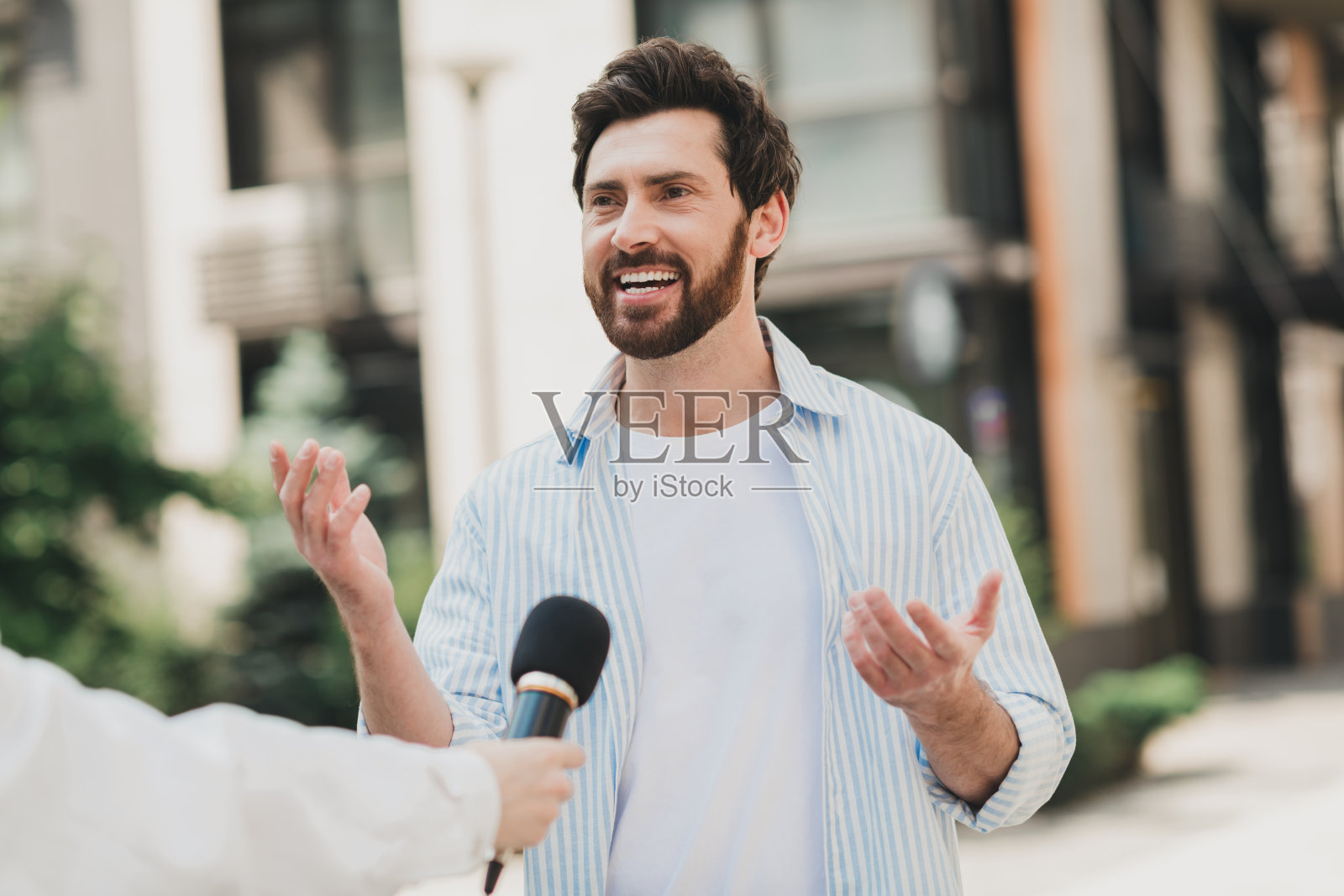 年轻男子在阳光明媚的城市景观中进行户外采访照片摄影图片