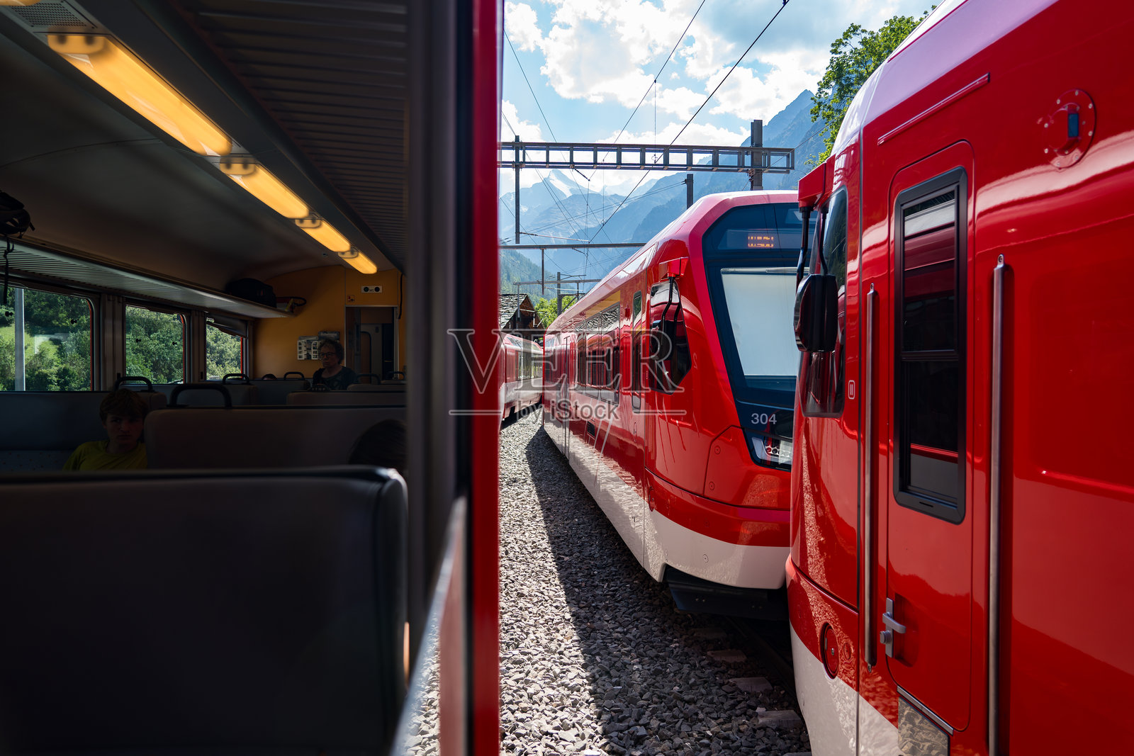 沿着图恩湖的火车之旅，途经图恩市、绿意盎然的田野和阿尔卑斯山房屋，前往瑞士的采尔马特。照片摄影图片