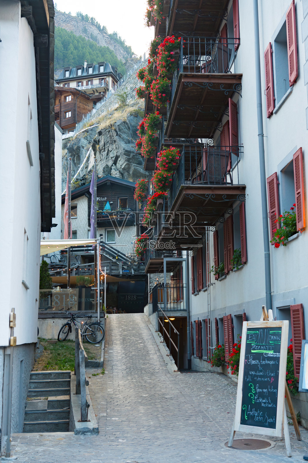 采尔马特市中心的傍晚景象,街道两旁有游客、餐馆、花卉和商店。照片摄影图片