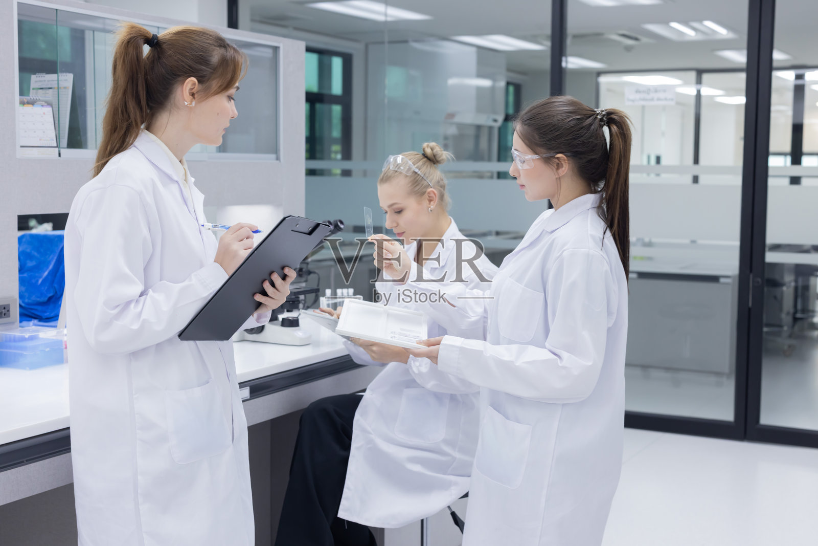 三位穿着实验室外套的科学家在实验室中进行讨论照片摄影图片