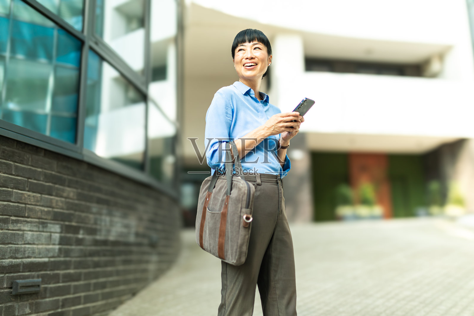 亚洲女商人在城市中微笑着使用手机照片摄影图片