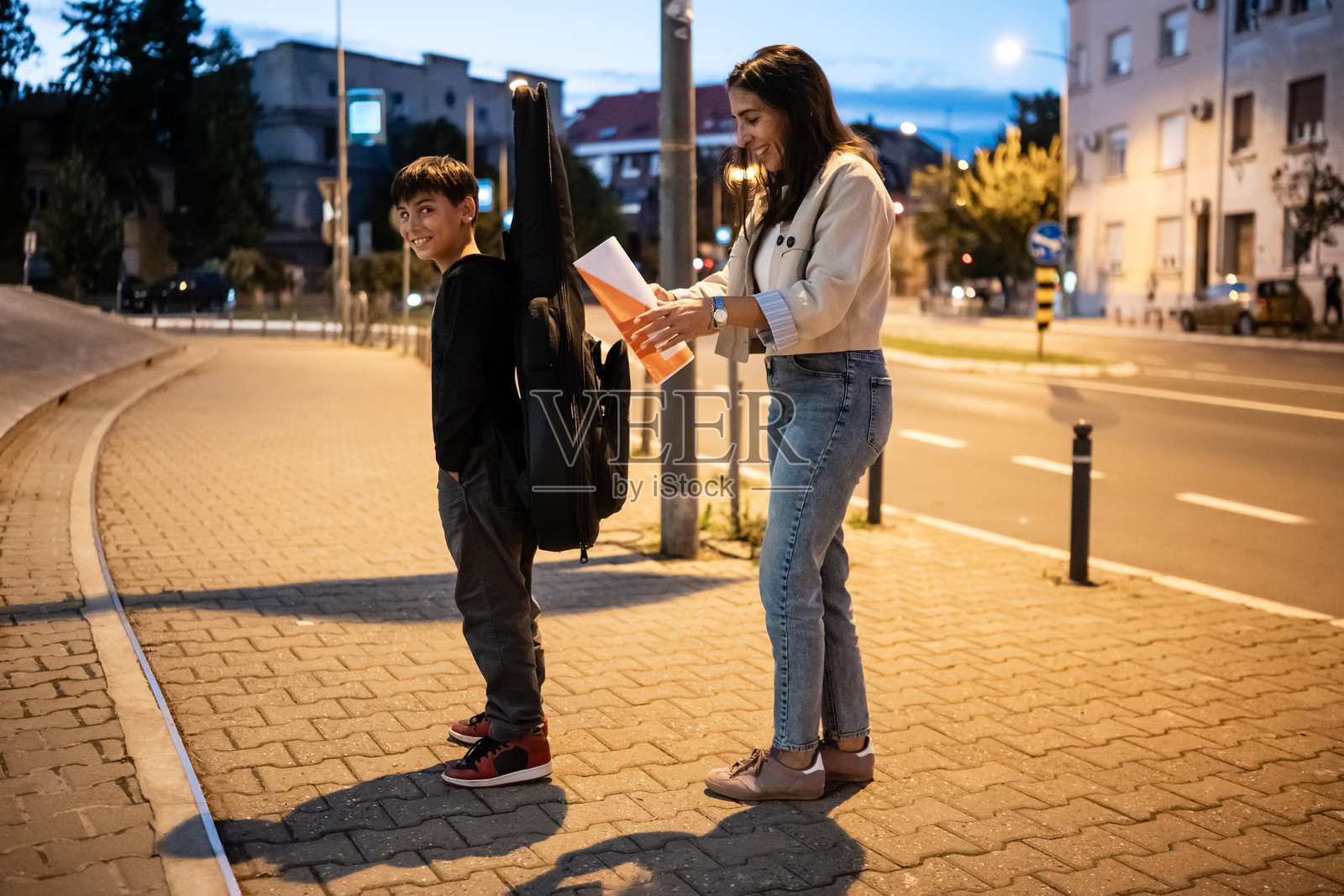 母亲在城市人行道上教儿子吉他课程照片摄影图片