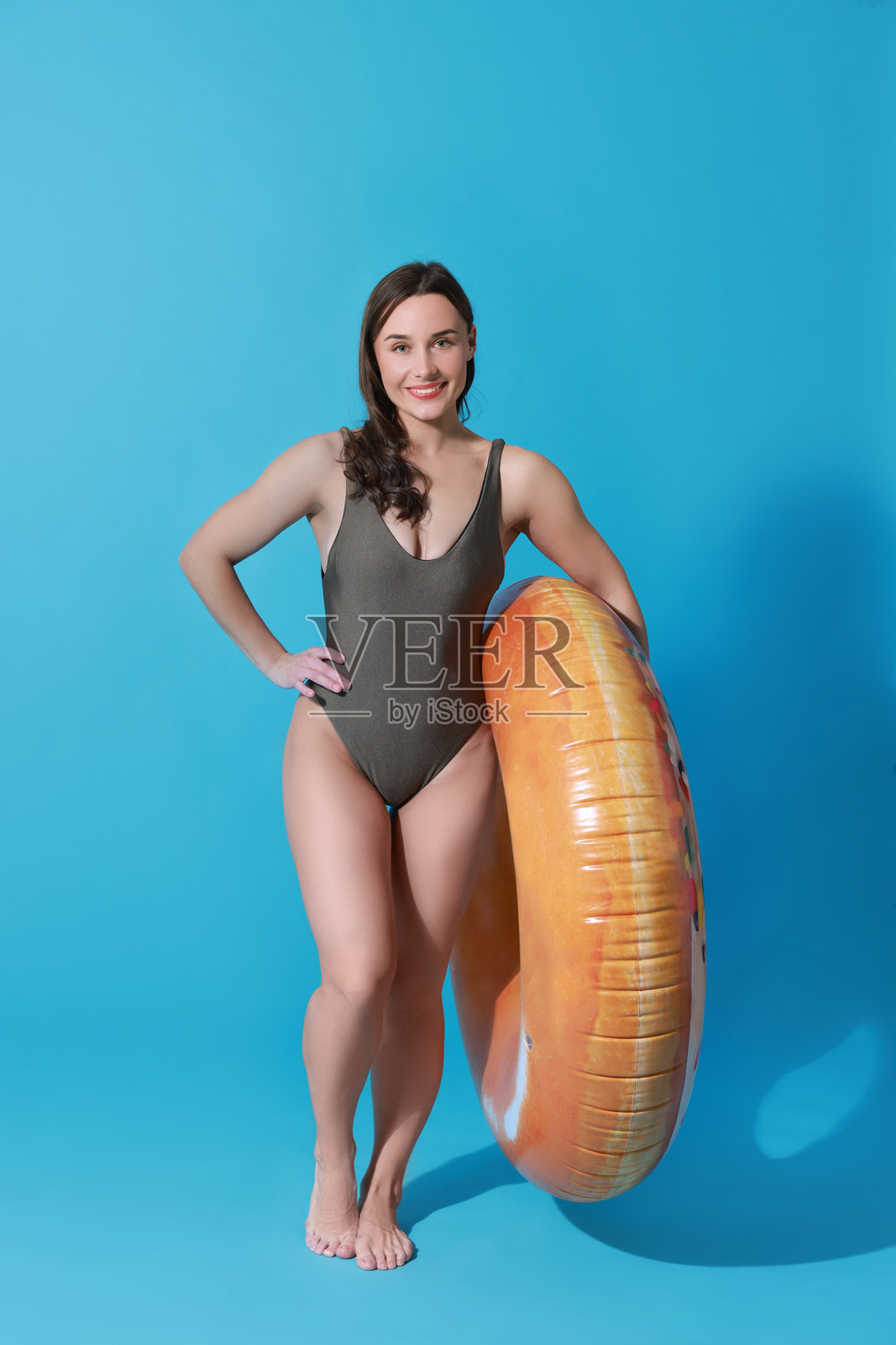 穿着泳衣的美丽女性与充气圈在浅蓝色背景上照片摄影图片