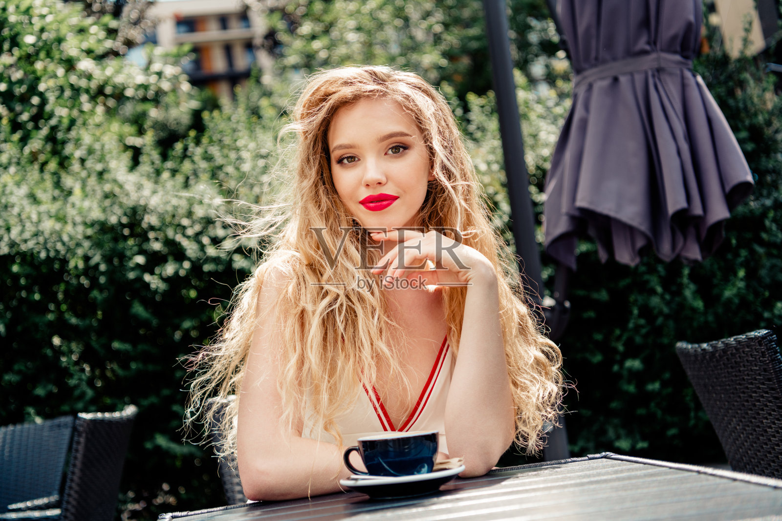 年轻女性在户外咖啡馆享受阳光明媚的一天，展现出美丽和生机勃勃的自然城市环境。照片摄影图片