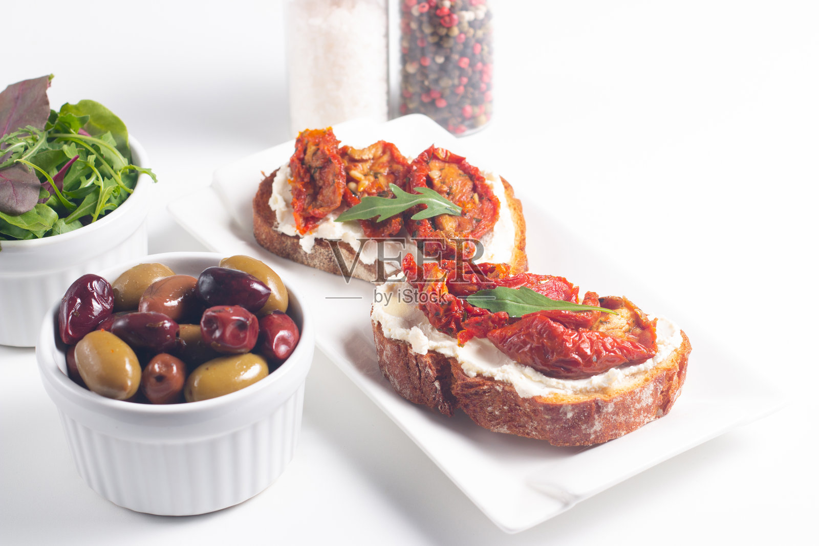 两片意式烤面包，上面放有干番茄、瑞可塔奶酪和芝麻菜。照片摄影图片