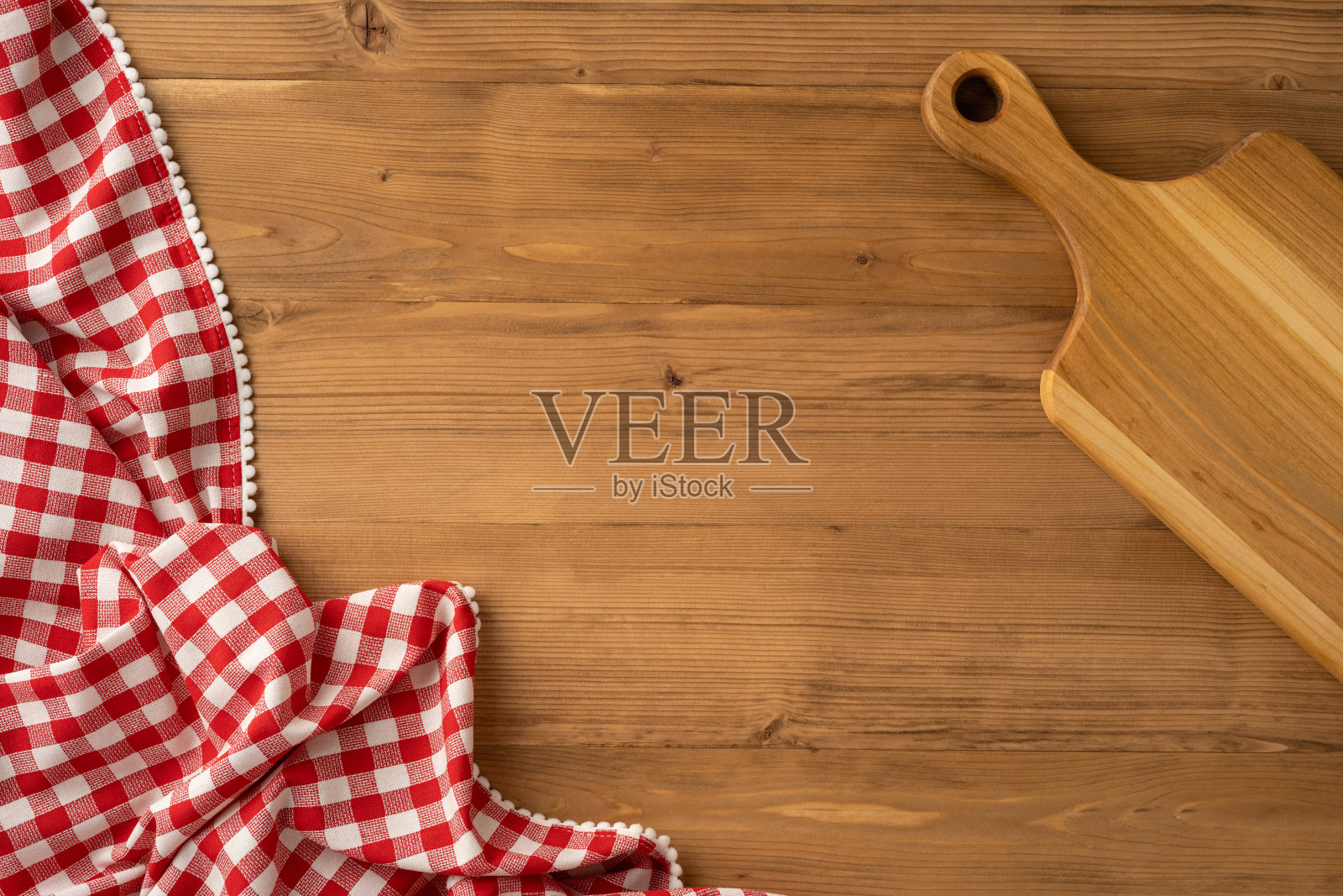 从上方俯视一张木桌，上面铺有格子布和一个木砧板照片摄影图片