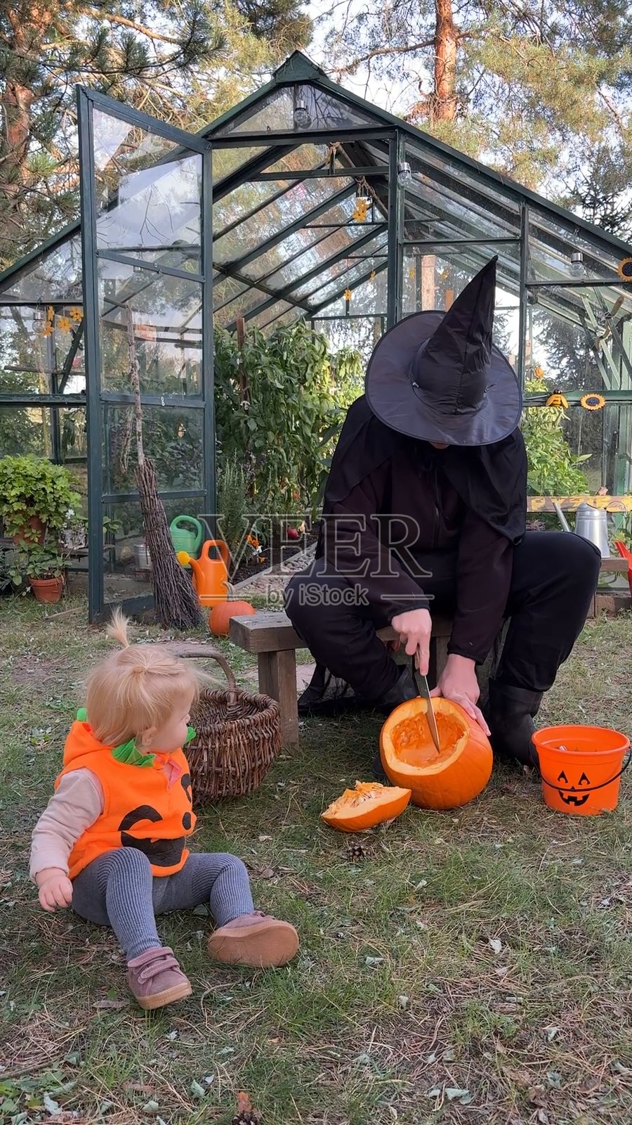 一个打扮成巫师的男孩，他的妹妹打扮成南瓜，他们的狗正在为万圣节做准备——他们在雕刻南瓜。照片摄影图片