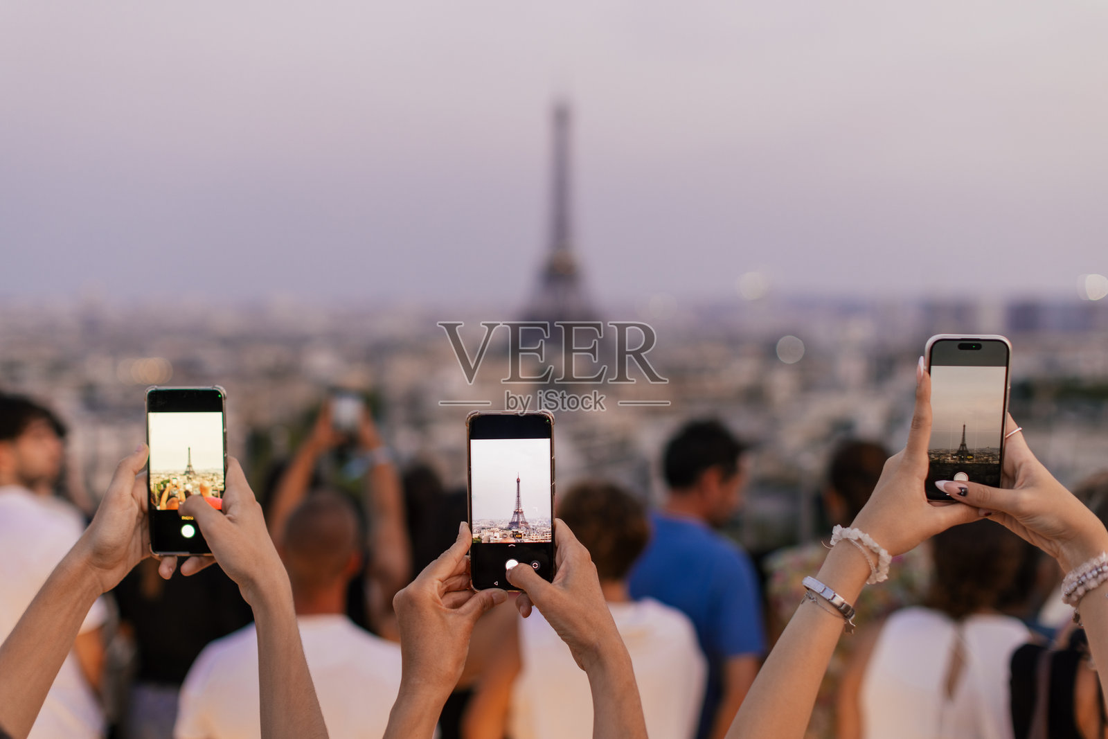 游客在黄昏时分观赏埃菲尔铁塔，并用手机拍照照片摄影图片