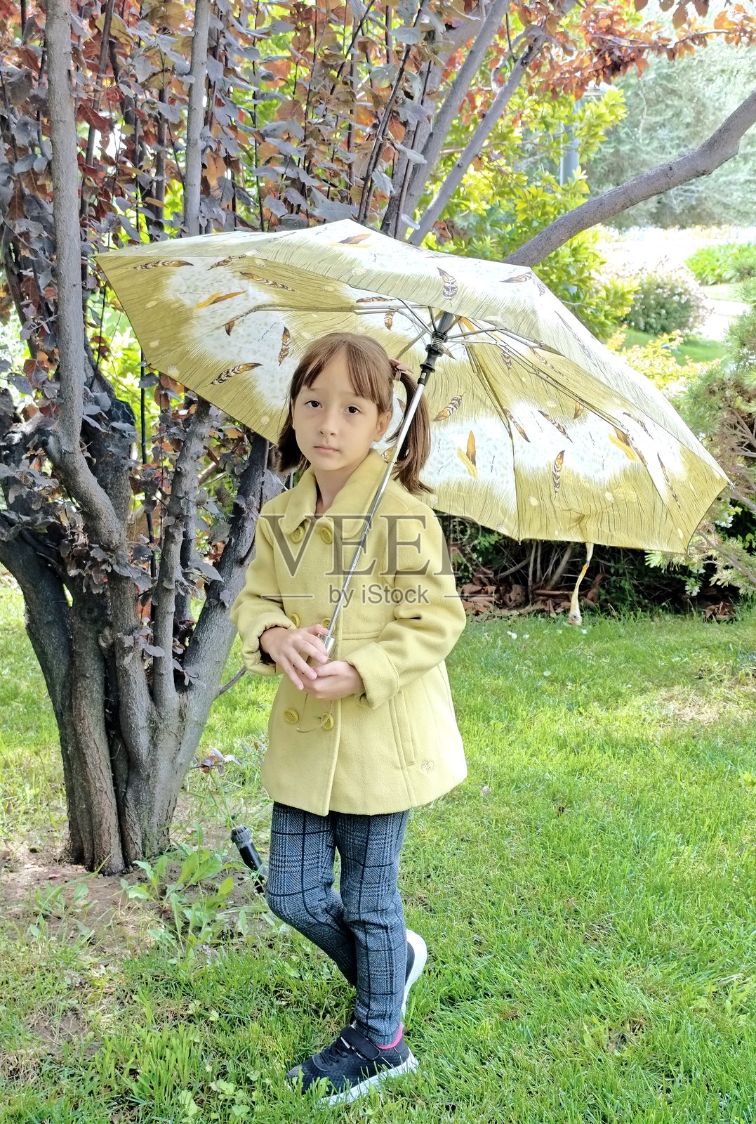 公园里拿着雨伞的小女孩照片摄影图片