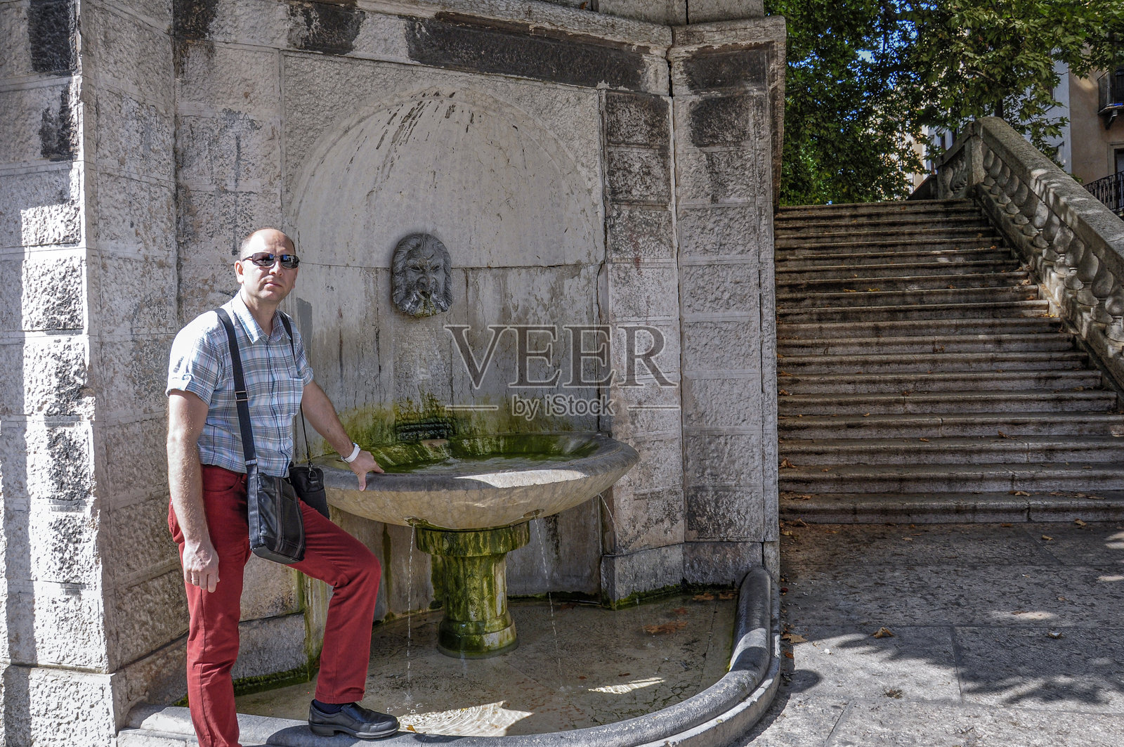 一位年轻的白人男性站在意大利维罗纳的马斯卡龙喷泉旁。照片摄影图片