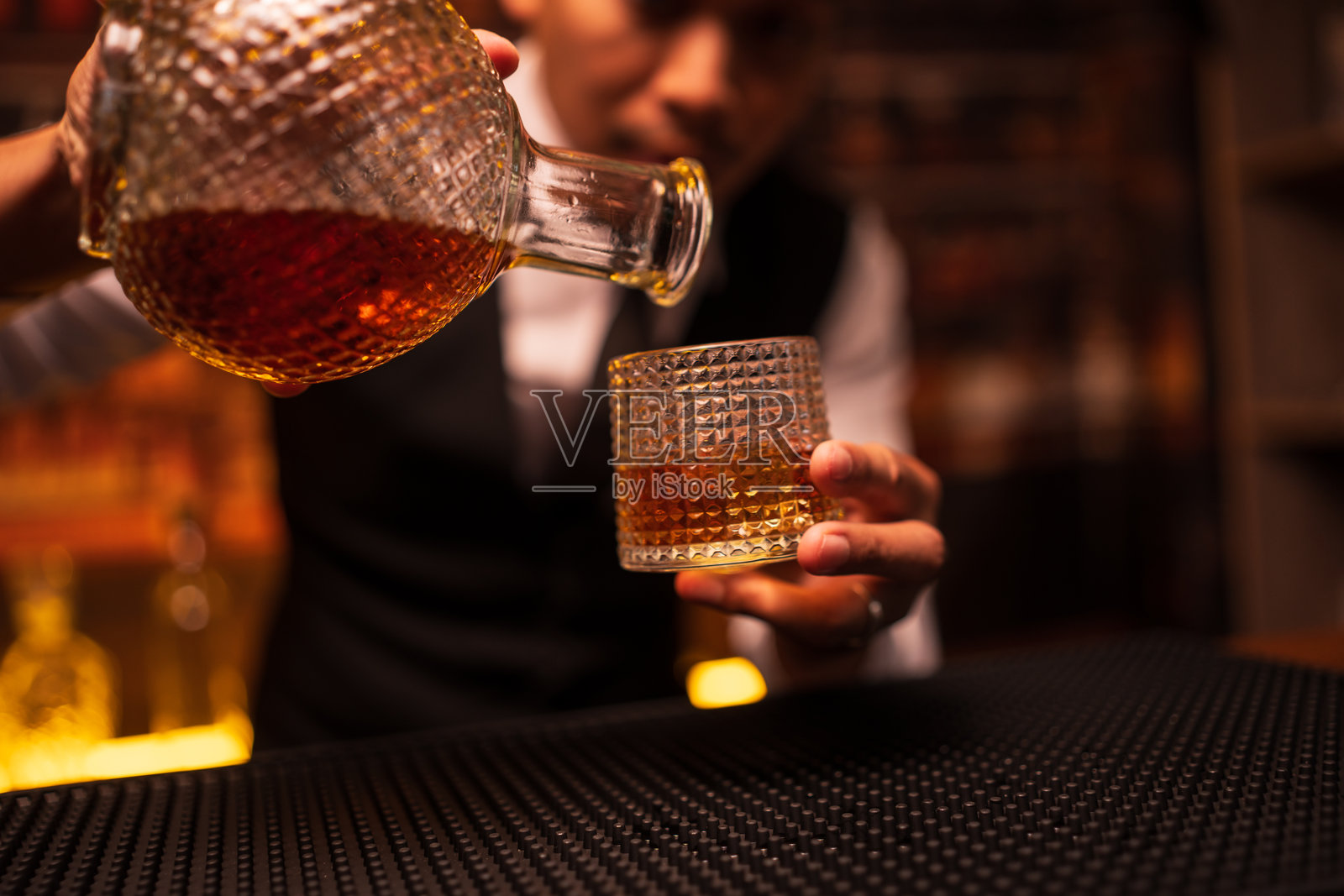 调酒师在餐厅里将威士忌倒入杯中照片摄影图片