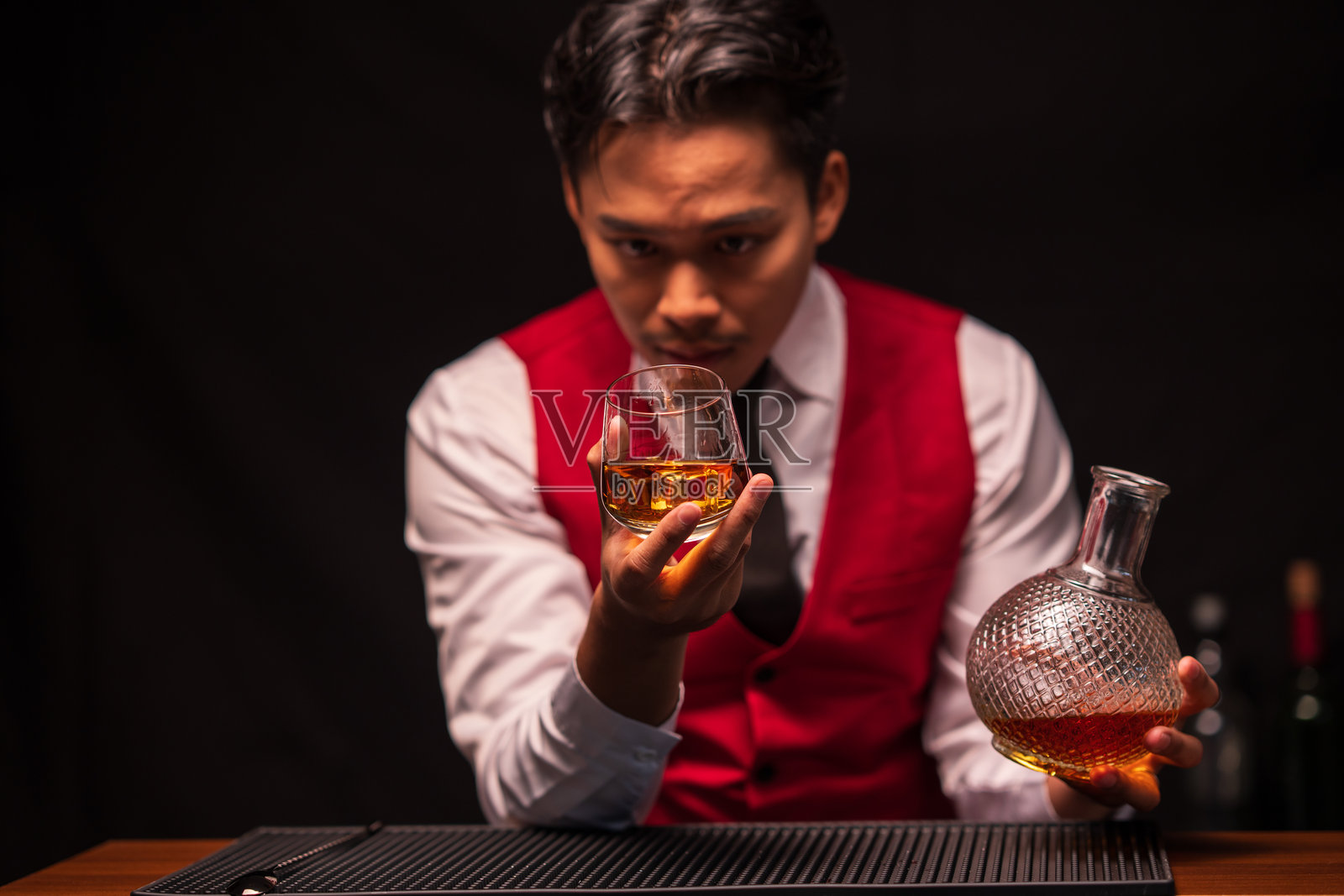 调酒师在餐厅里往杯子里倒威士忌照片摄影图片