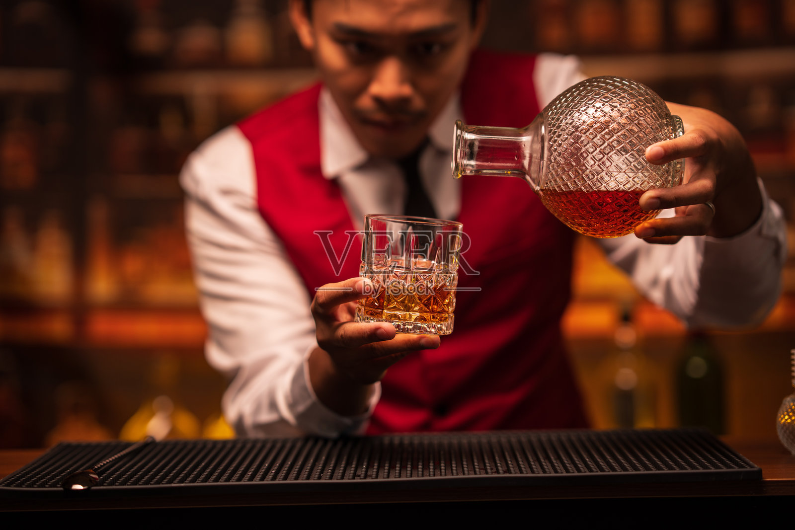 调酒师在餐厅里往杯子里倒威士忌照片摄影图片