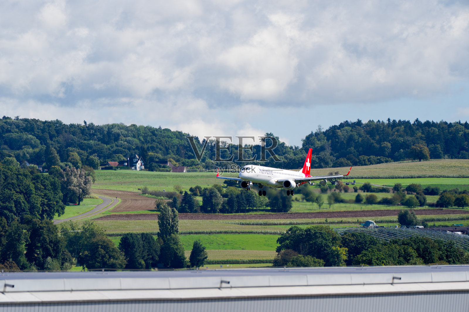 夏末时节，瑞士航空（Helvetic Airways）注册号为HB-JVA的巴西航空工业公司ERJ-195型客机正在苏黎世克洛滕机场（Zürich Kloten Airport）降落。照片摄影图片
