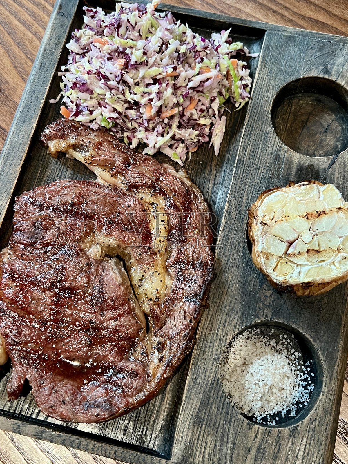 盐烤牛排，配凉拌卷心菜和烤大蒜照片摄影图片