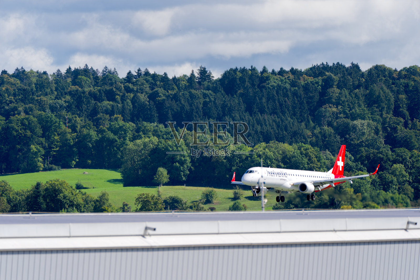 夏末时分，瑞士航空（Helvetic Airways）的ERJ-195型客机（注册号HB-JVA）正在苏黎世克洛滕机场（Zürich Kloten Airport）降落。照片摄影图片