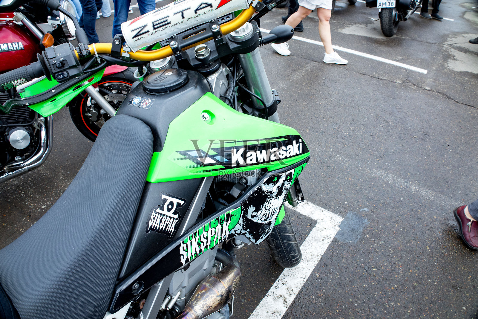 阴天时，在热闹的户外聚会上，一辆亮绿色的摩托车展示着摩托车爱好者及其座驾，背景是充满活力的城市。照片摄影图片