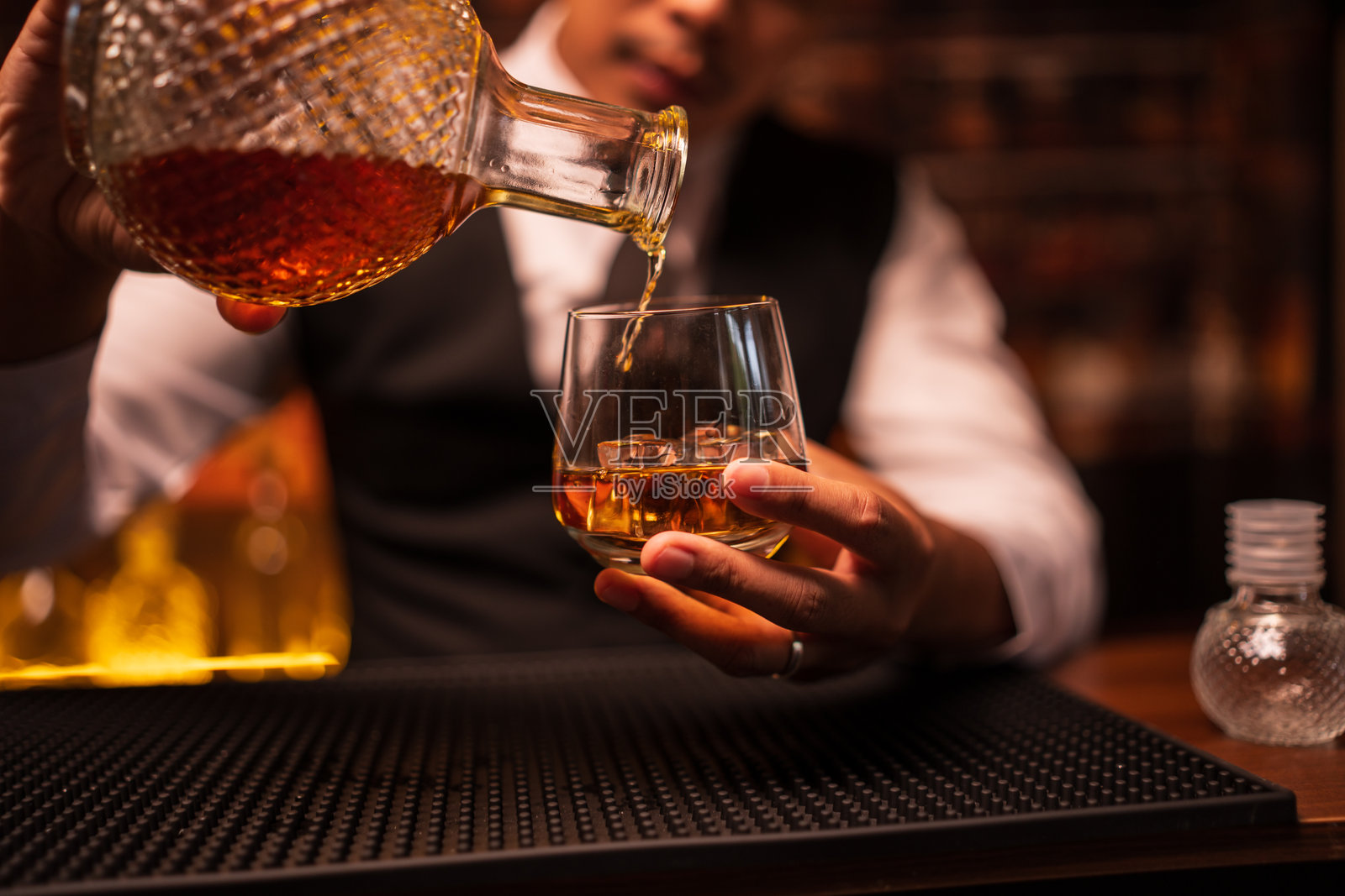 酒保正在餐厅里向酒杯中倒威士忌照片摄影图片