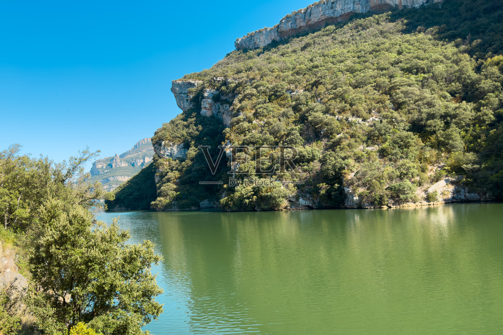 西班牙阿尔瓦与布尔戈斯交界处的埃布罗河索布龙水库的风景，周围环绕着绿色的山脉和戏剧性的岩石构造。照片摄影图片