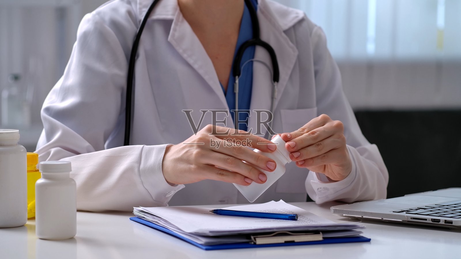 医生在医疗办公室的桌子旁检查药瓶照片摄影图片