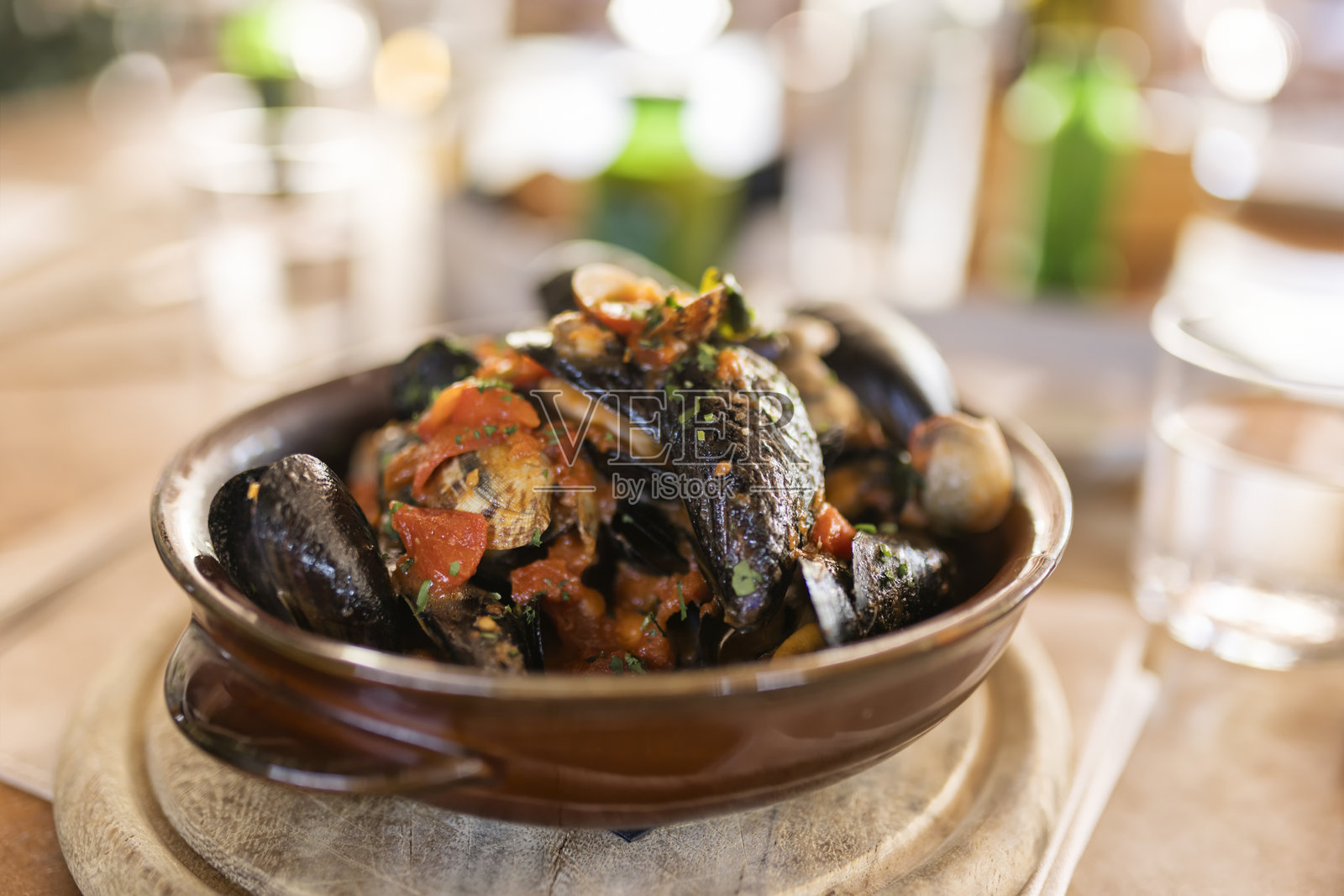 意大利餐厅陶瓷碗中番茄香草汤汁炖煮的贻贝和蛤蜊特写照片摄影图片