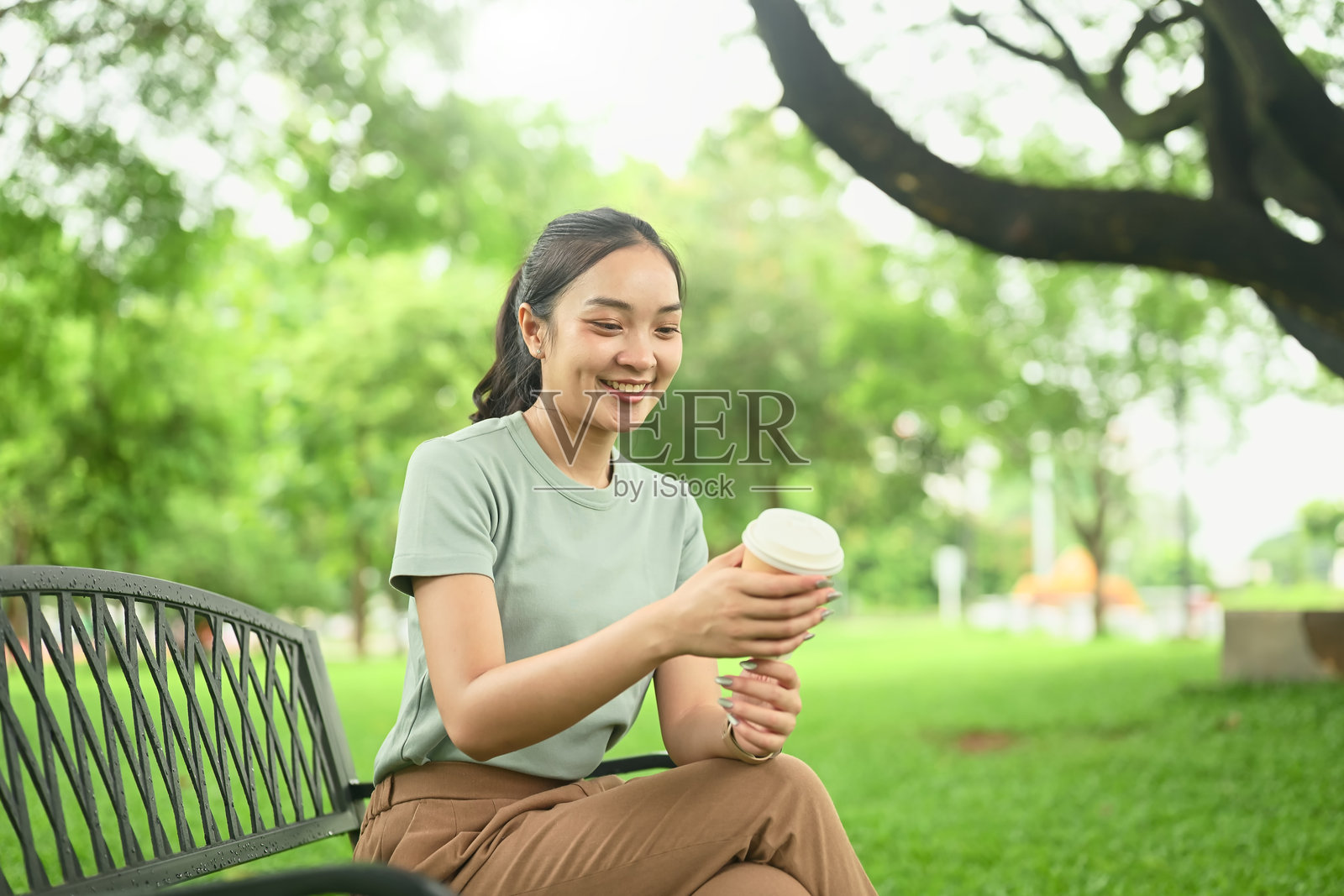 一位穿着休闲装的快乐年轻女子在宁静的自然环境中享用热饮照片摄影图片