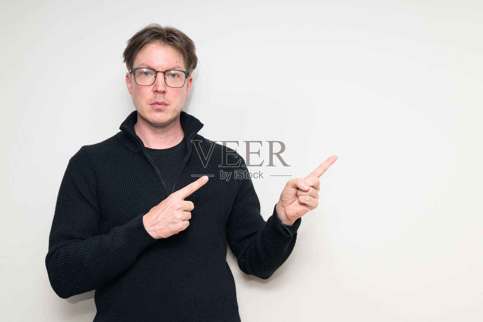 身穿黑色毛衣的斯堪的纳维亚中年男子肖像，手指指向前方，背景为白色。照片摄影图片