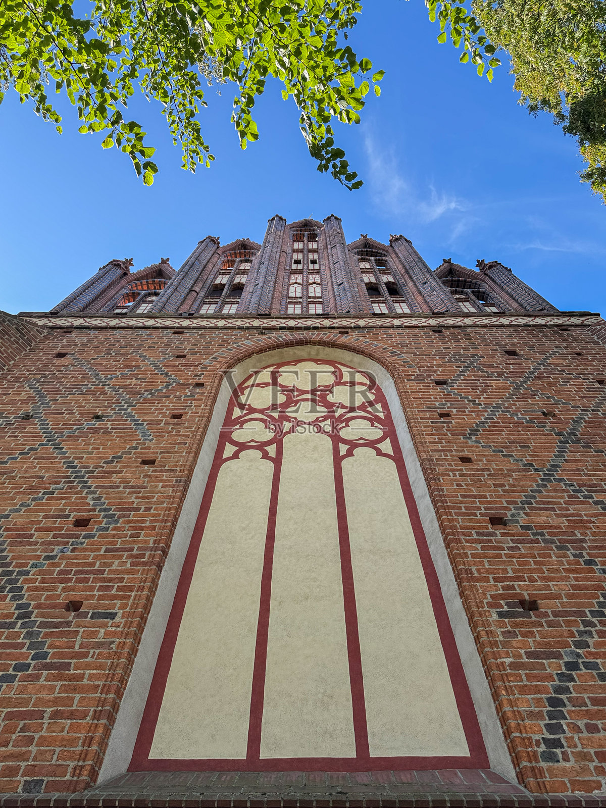 向上看哥特式砖砌教堂正面，带有彩绘设计照片摄影图片