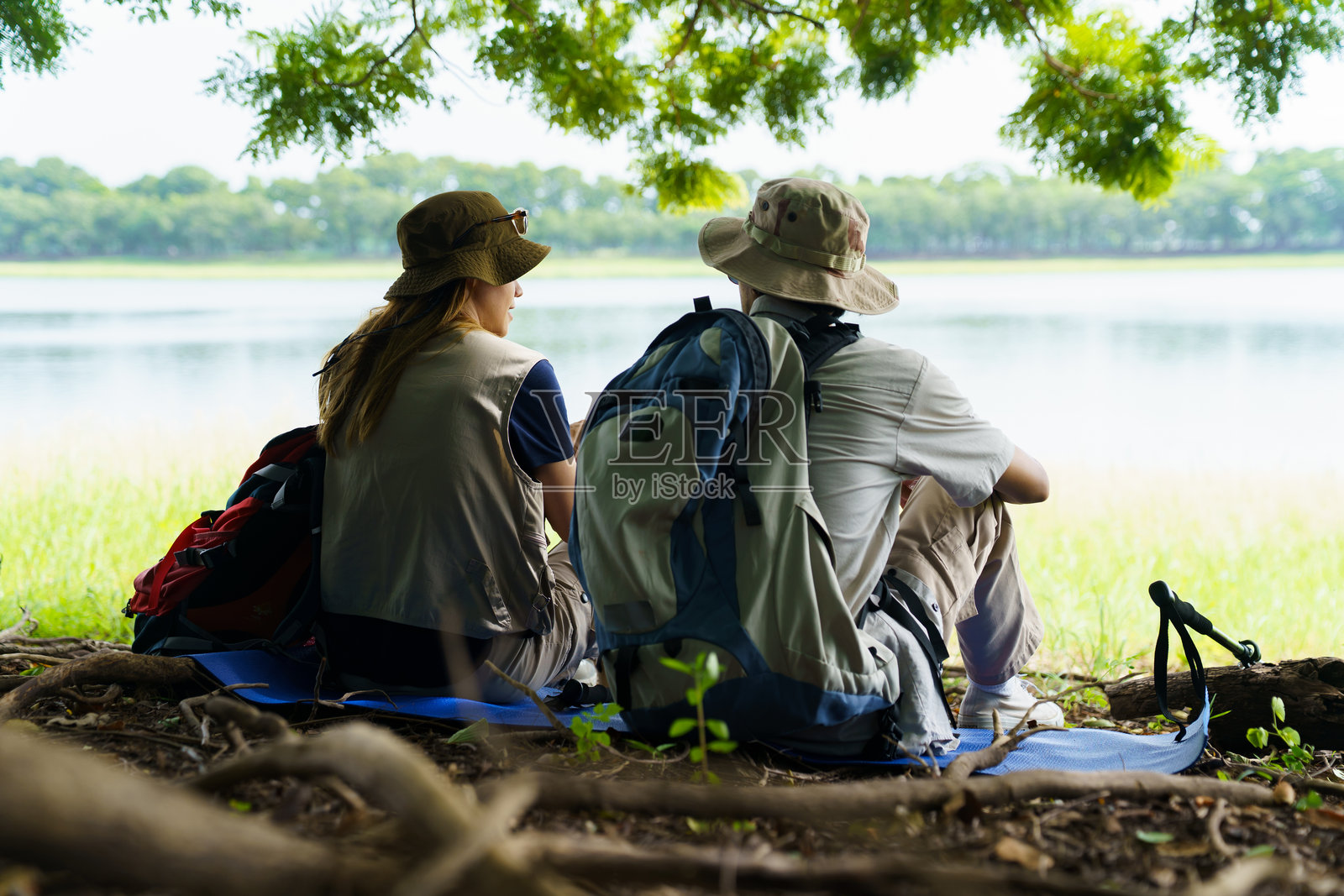 徒步旅行者在湖边草地旁的树下休息照片摄影图片