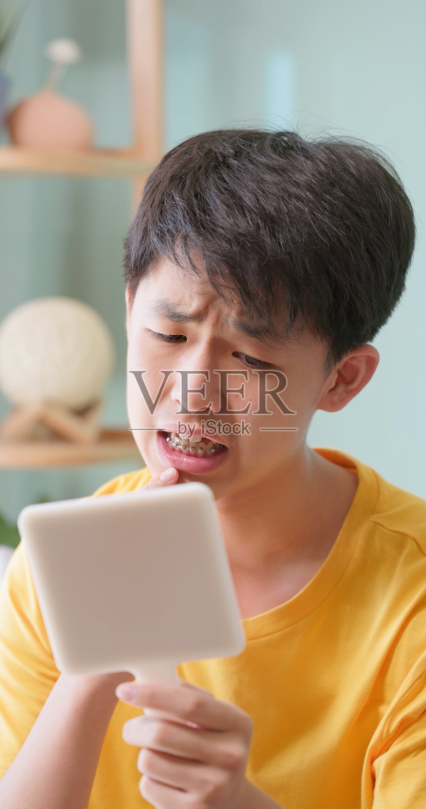 少女在镜子前看着牙套，感到沮丧照片摄影图片