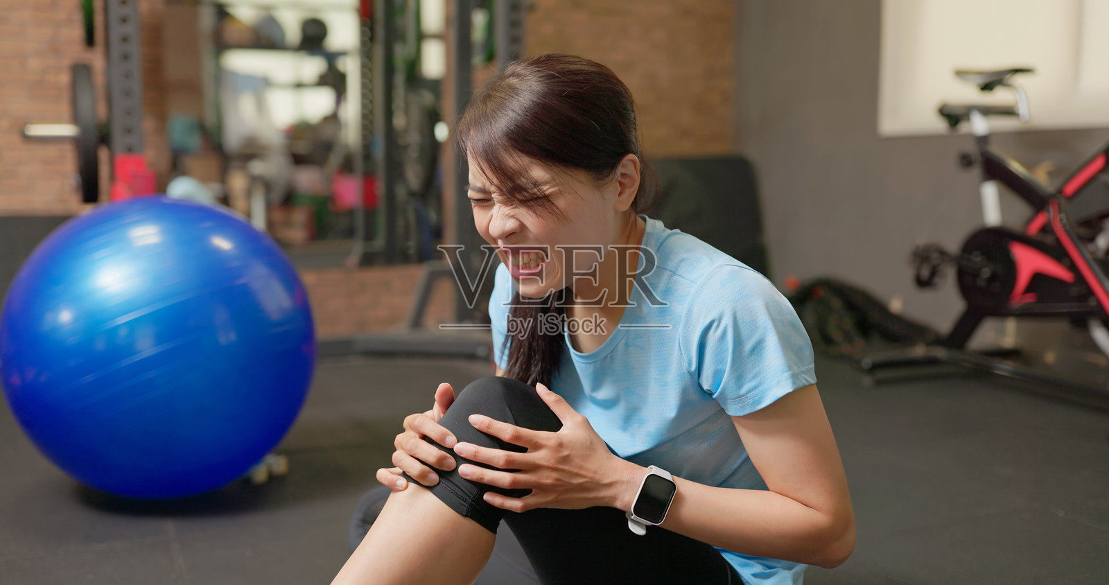 亚洲女性在健身房锻炼时遭受膝盖疼痛照片摄影图片