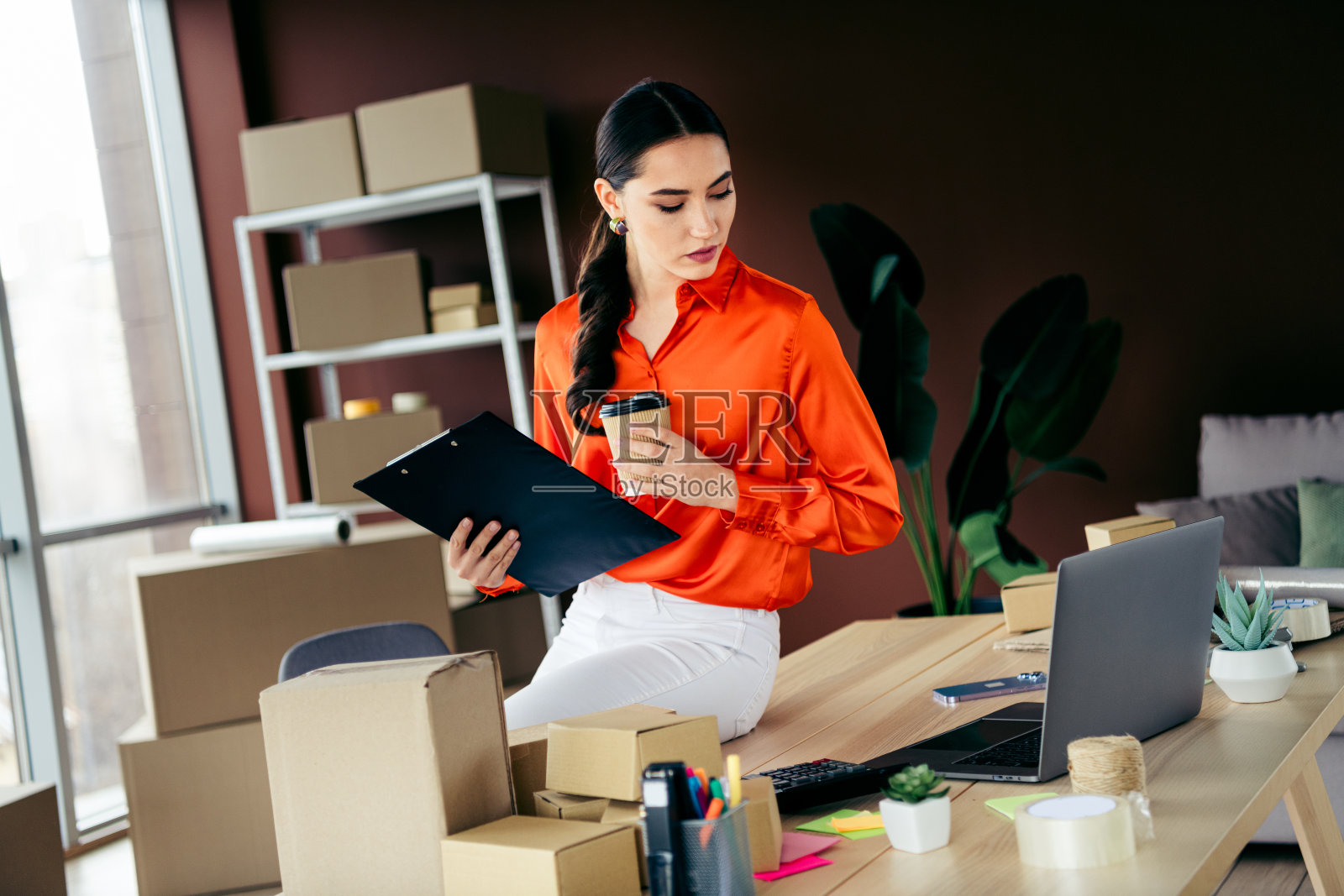 年轻的女企业家在时尚的现代办公室工作空间整理包裹并管理电子商务订单照片摄影图片