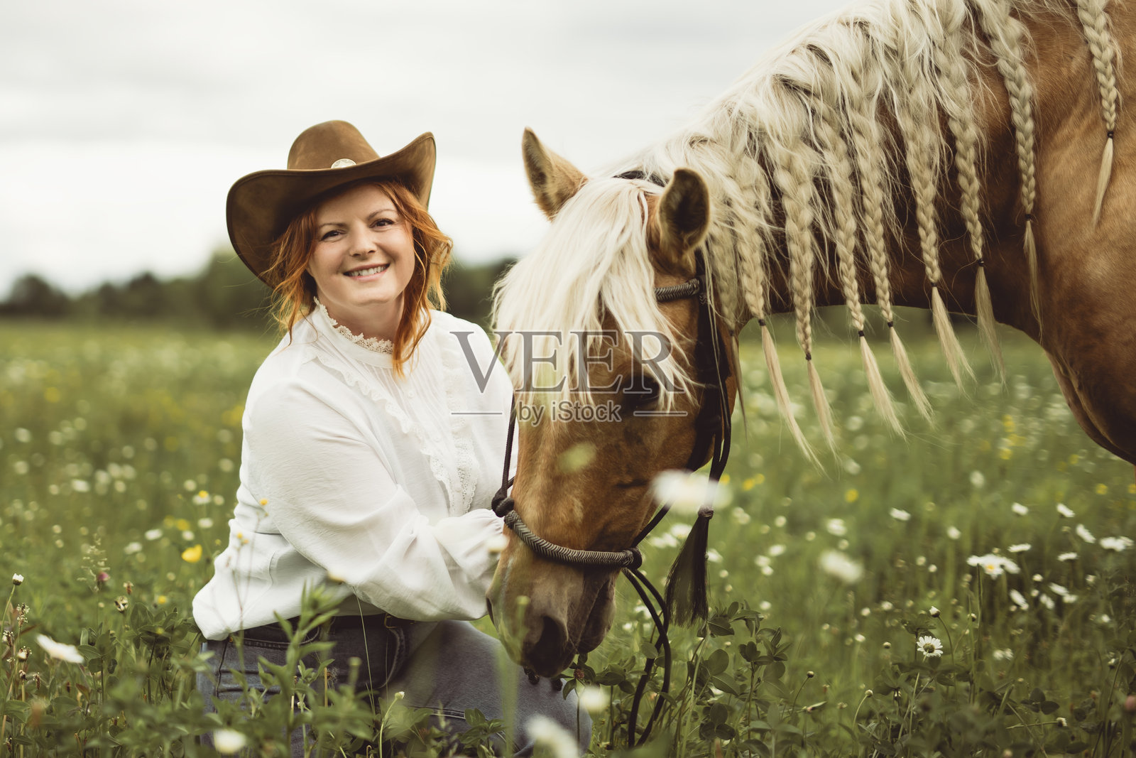 一位女士戴着牛仔帽，在开阔的田野里骑马。照片摄影图片