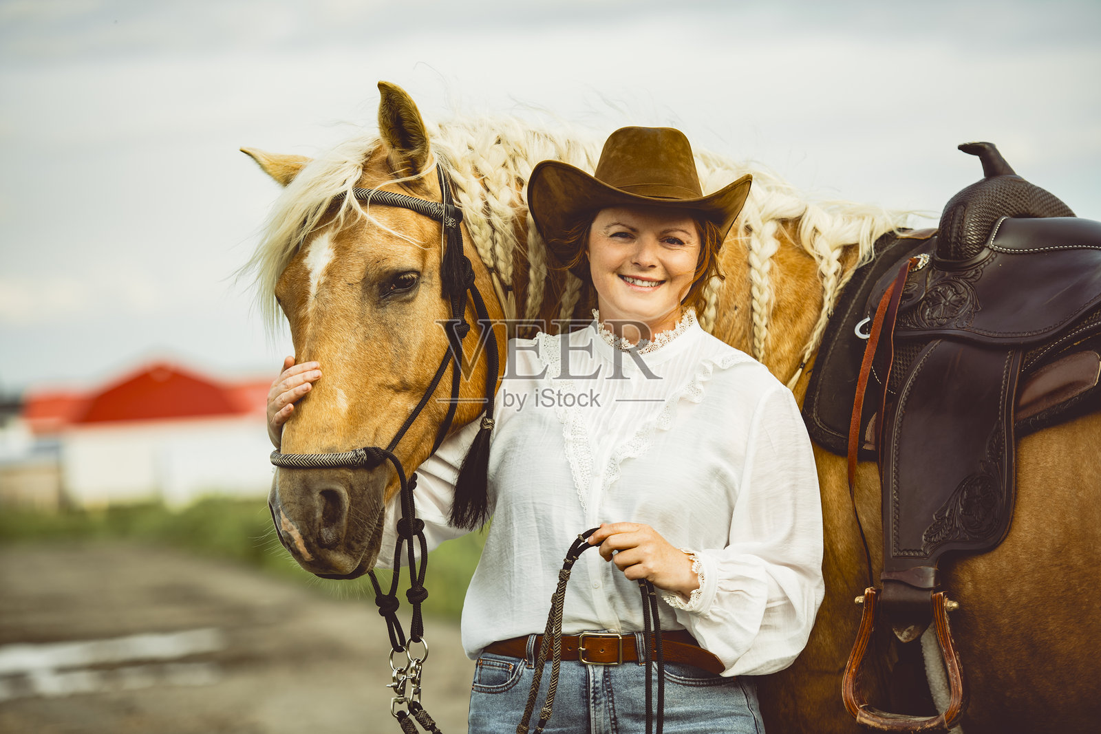 一位女士自豪地戴着牛仔帽，站在她的马旁边照片摄影图片