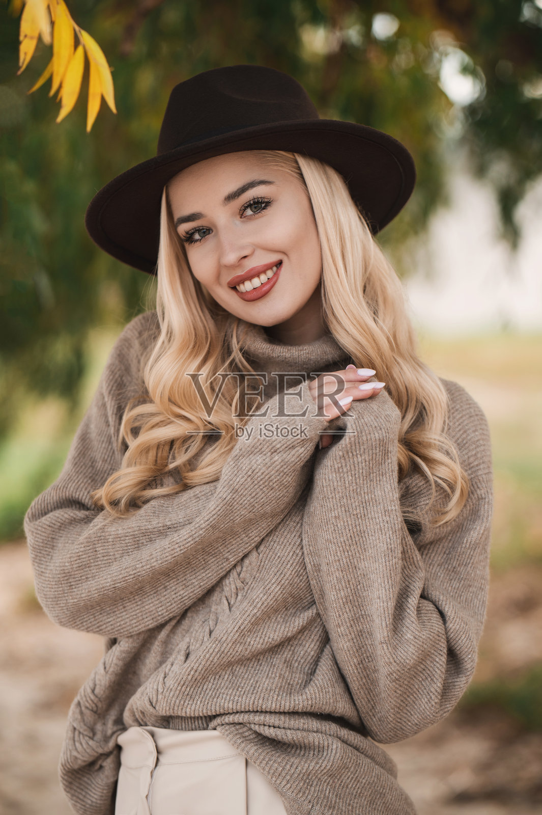 秋日暖阳，时髦女士戴着帽子、穿着外套在户外漫步。照片摄影图片