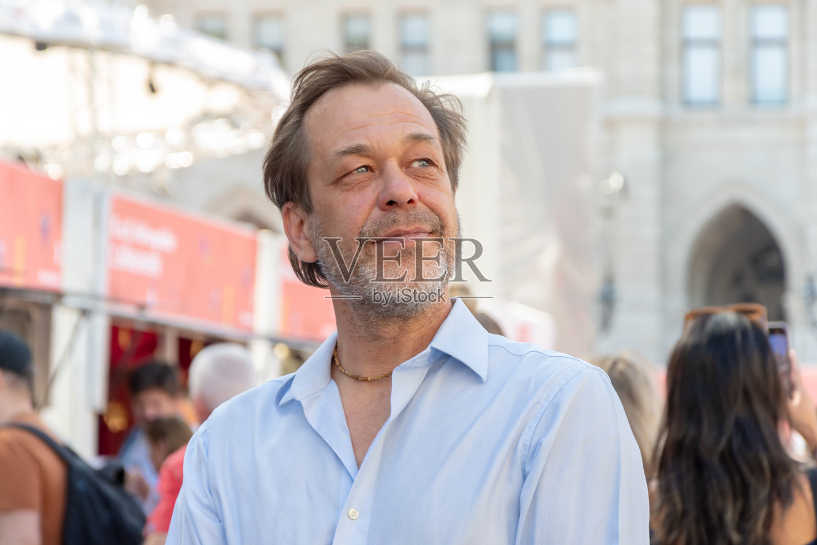 人群背景下自信的中年男子肖像。照片摄影图片
