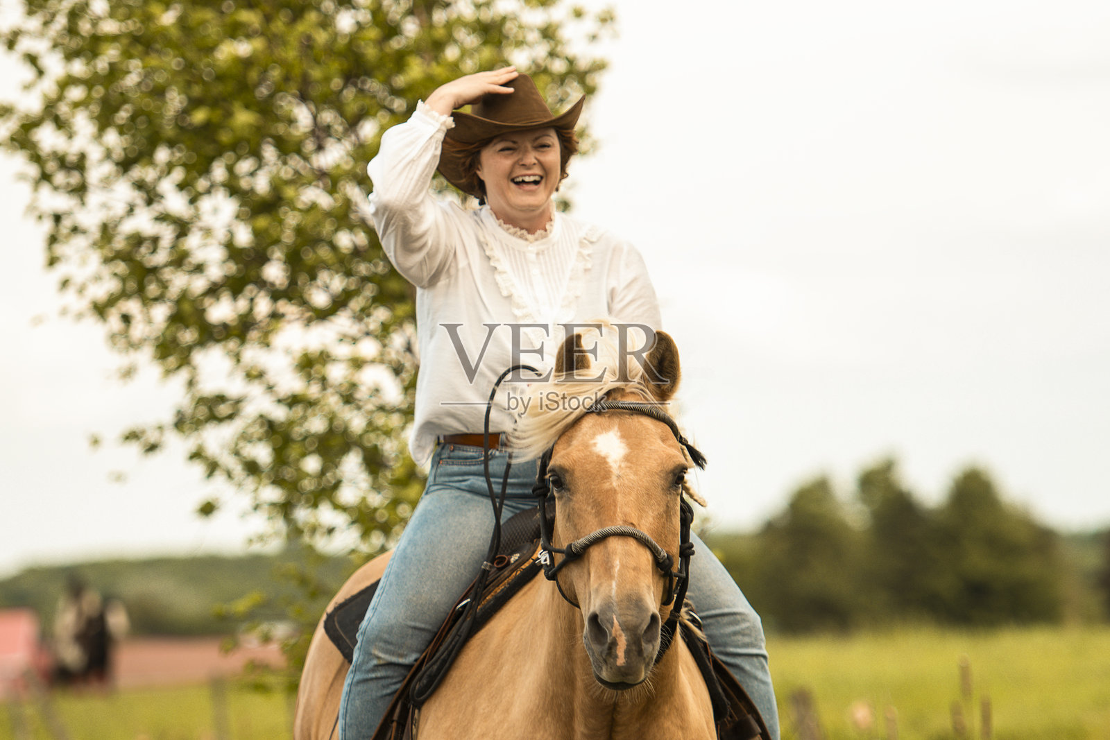 一位女士在绿意盎然的田野里，优雅地熟练骑马。照片摄影图片