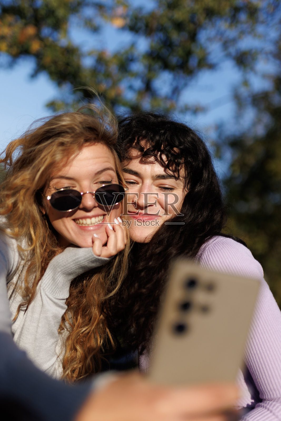 朋友们在阳光明媚的户外享受时光，在有树木作为背景的自然环境中，通过自拍捕捉欢乐瞬间。照片摄影图片
