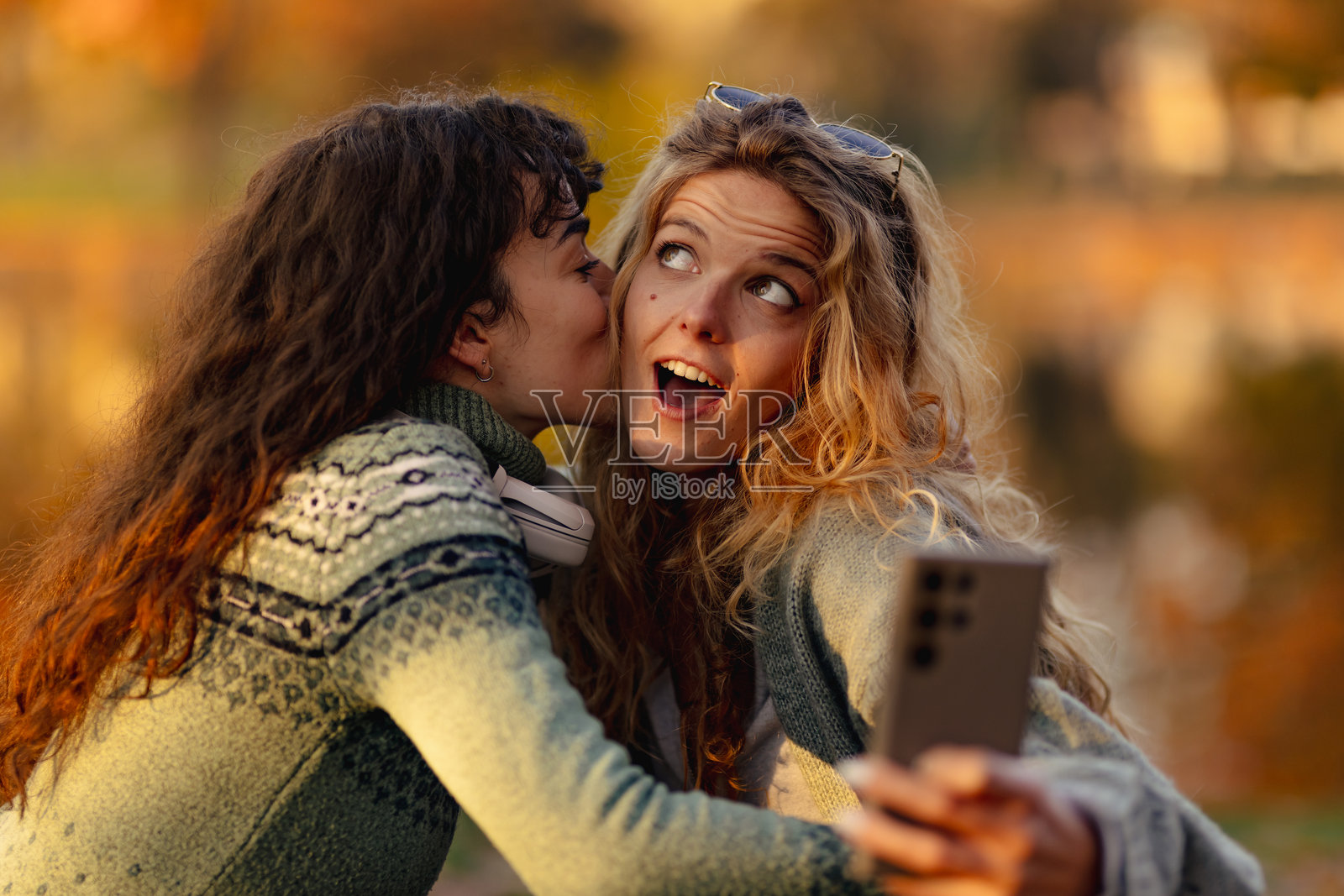 秋天，朋友们在水边，看着落叶变色，享受着自拍的欢乐时光，周围环境宁静祥和。照片摄影图片