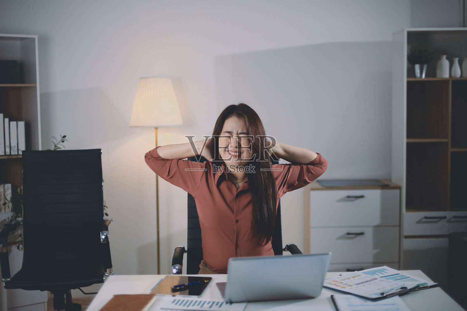 一位迷人的亚洲女商人在长时间久坐后，在办公室放松身心，以避免办公室综合征。照片摄影图片