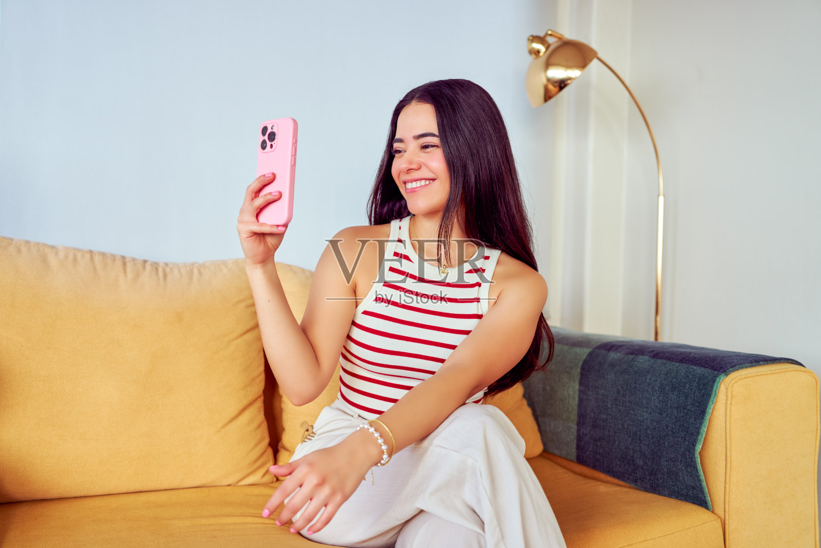 年轻的拉丁裔女性在家用智能手机进行视频通话照片摄影图片