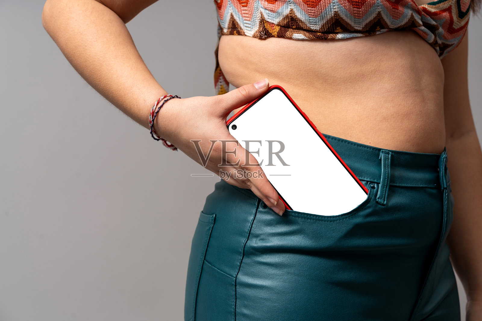女子将带有空白屏幕的智能手机放入口袋照片摄影图片