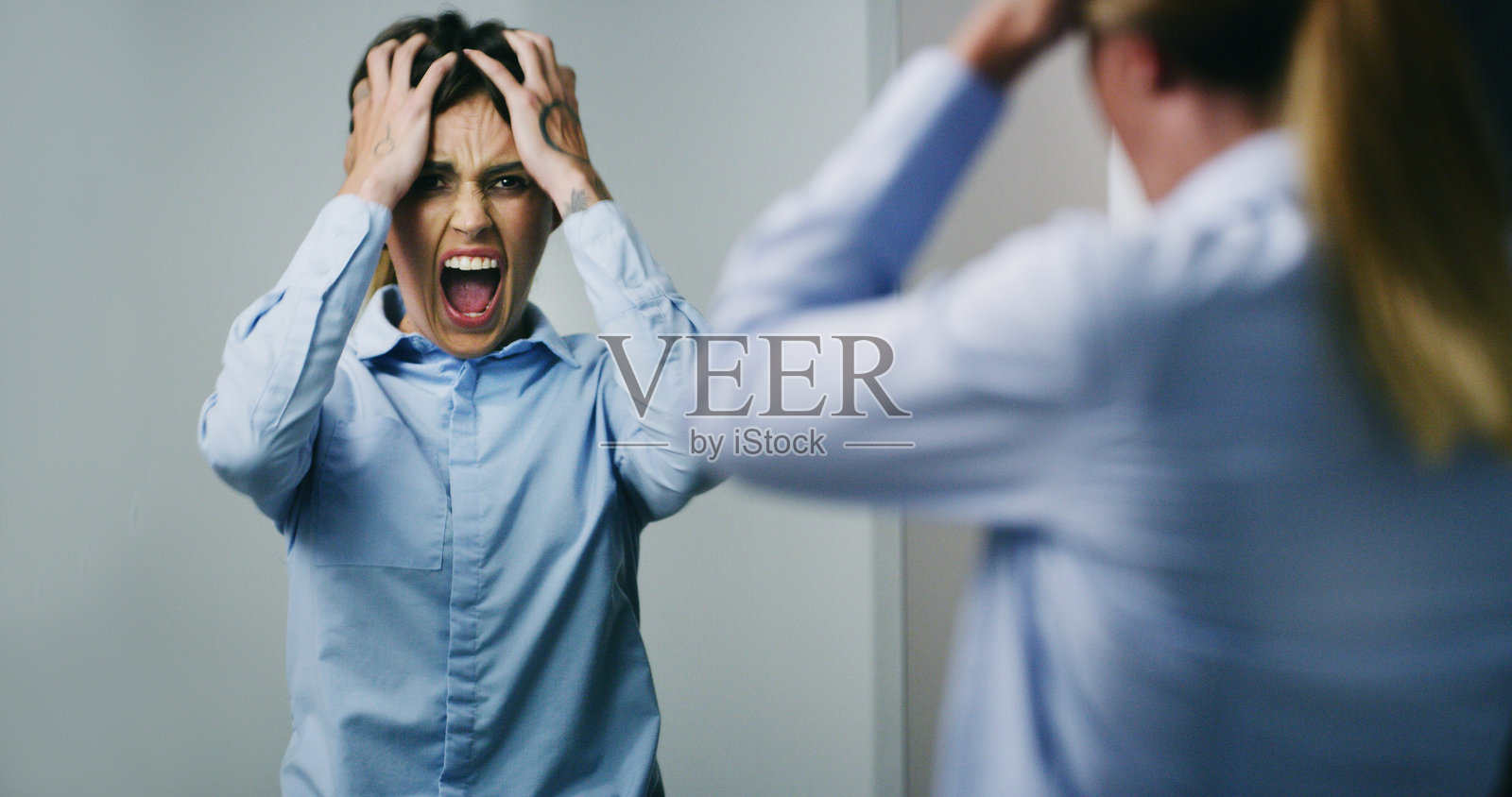 一位员工，一位女性，手持镜子，因失业而尖叫、沮丧，表现出恐慌或大喊。这反映了心理健康问题，以及因金融危机、被解雇或炒鱿鱼而感到的不快乐和焦虑。照片摄影图片