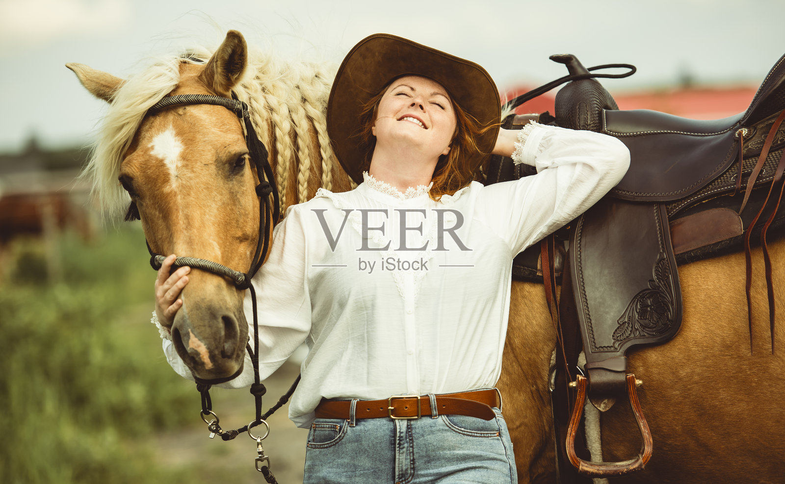 一位女士自豪地戴着牛仔帽，站在她的马旁边照片摄影图片