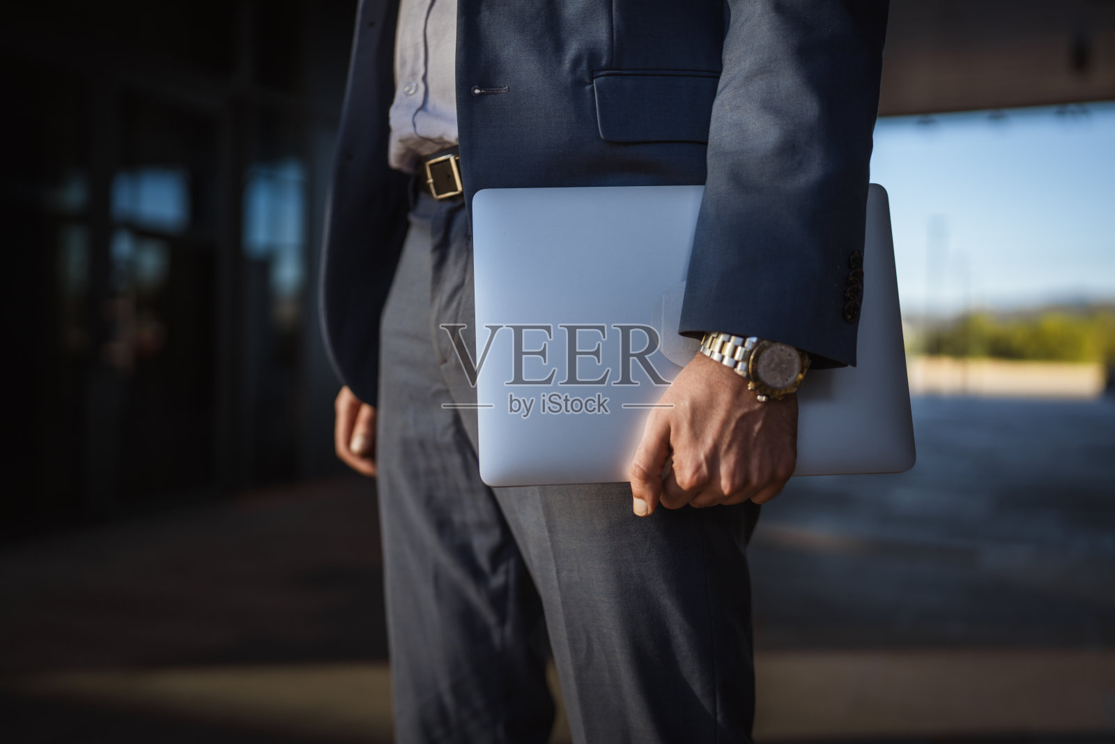 商务人士在现代办公楼里拿着笔记本电脑行走照片摄影图片