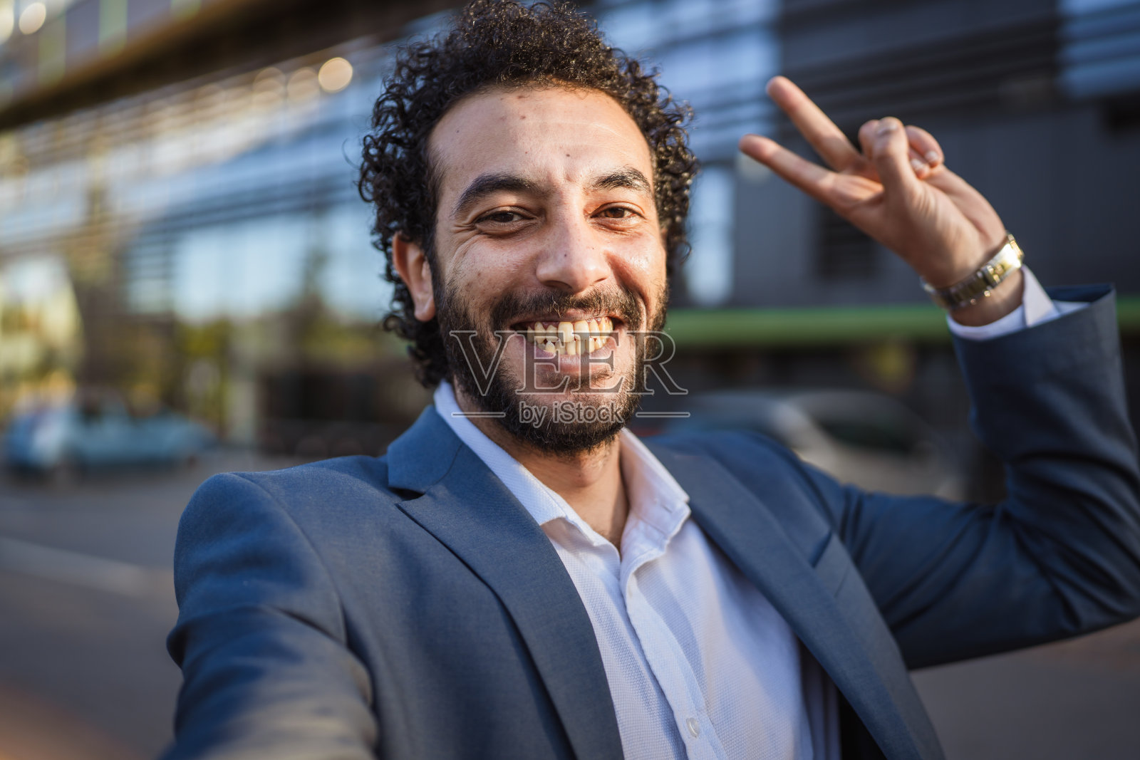 一位微笑着的商人正在城市街道上做出胜利手势照片摄影图片