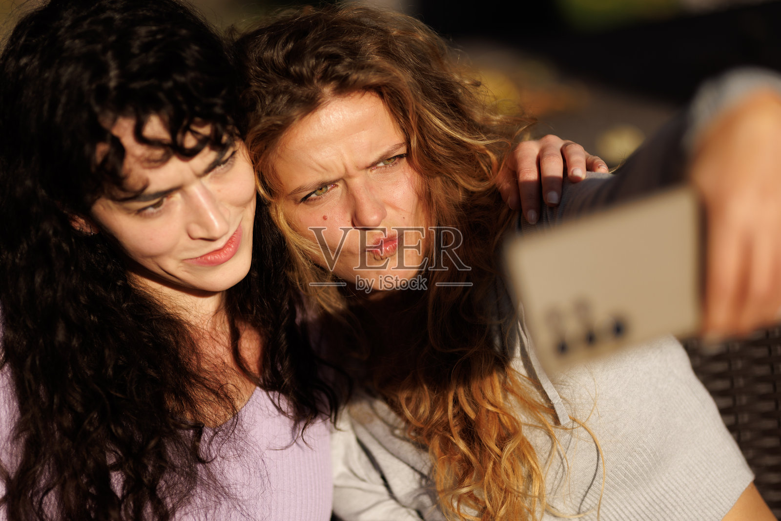 两个朋友在公园里一起享受阳光灿烂的一天，同时自拍。照片摄影图片