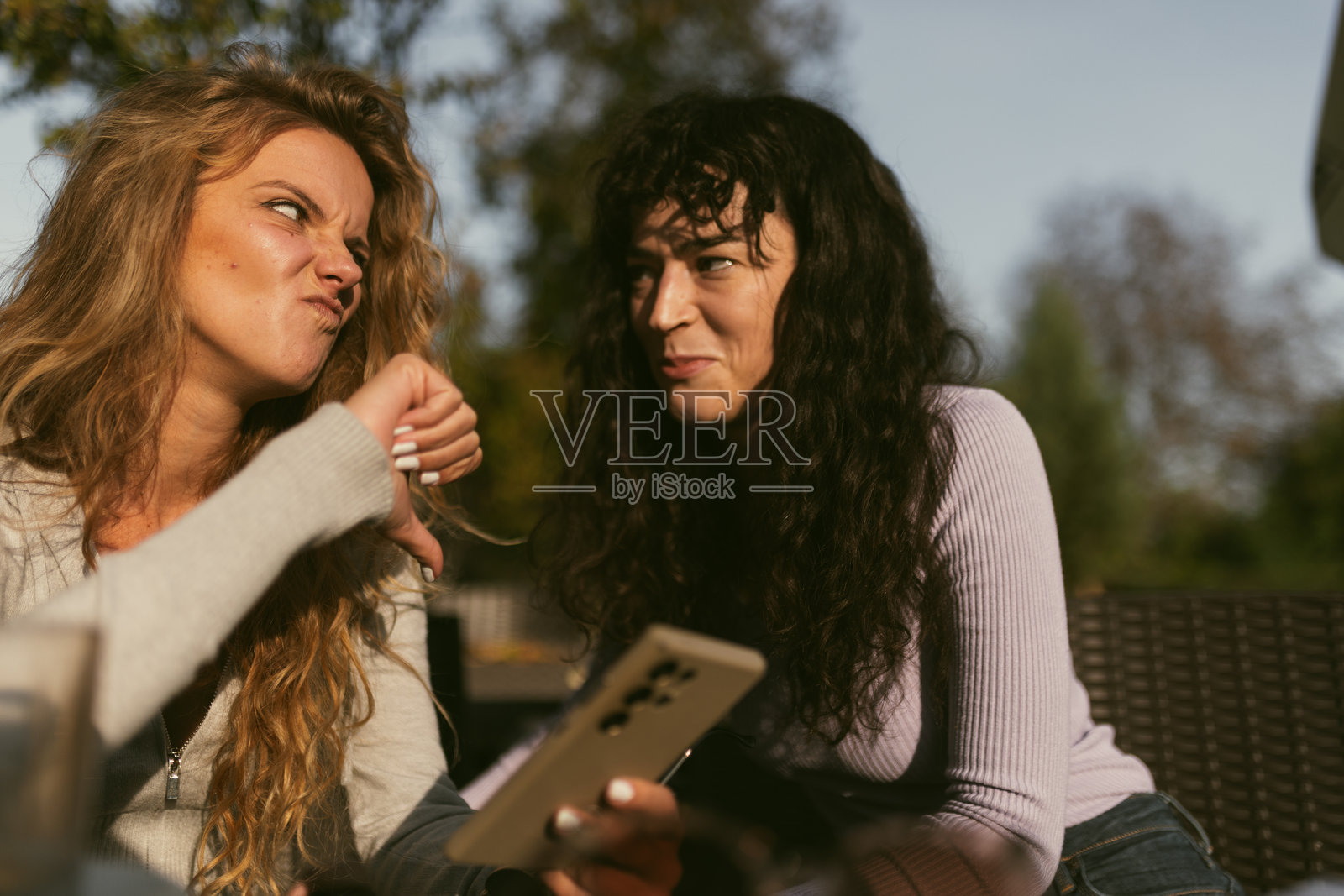 两个朋友在阳光明媚的下午户外分享着轻松愉快的时刻，进行着有趣的谈话。照片摄影图片