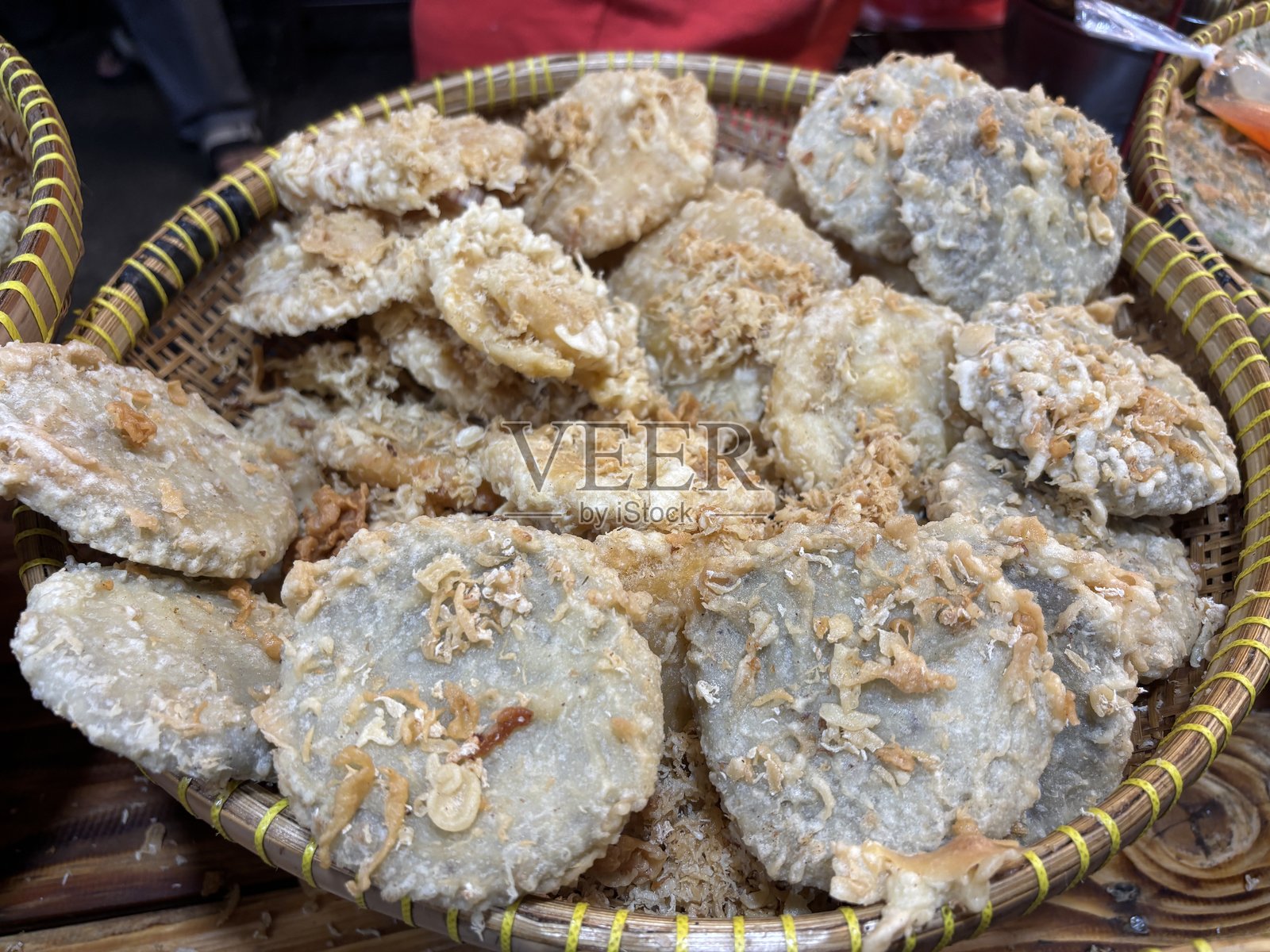 Golden fried sweet potato slices served in a woven bamboo tray, a traditional Indonesian street snack made from batter-fried root vegetables.照片摄影图片